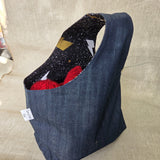 Blue denim fabric bag with black and gold fabric interior on a neutral background