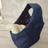 Blue denim fabric bag with black and gold fabric interior on a neutral background