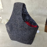 Black tweed-like fabric bag with black fabric interior on a neutral background